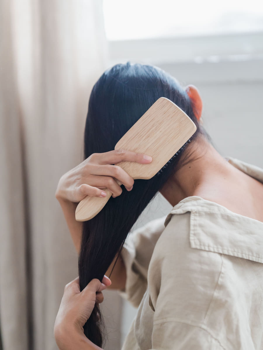 Long dark hair brushed smooth in warm light, the finish a keratin or nanoplastia treatment aims for.